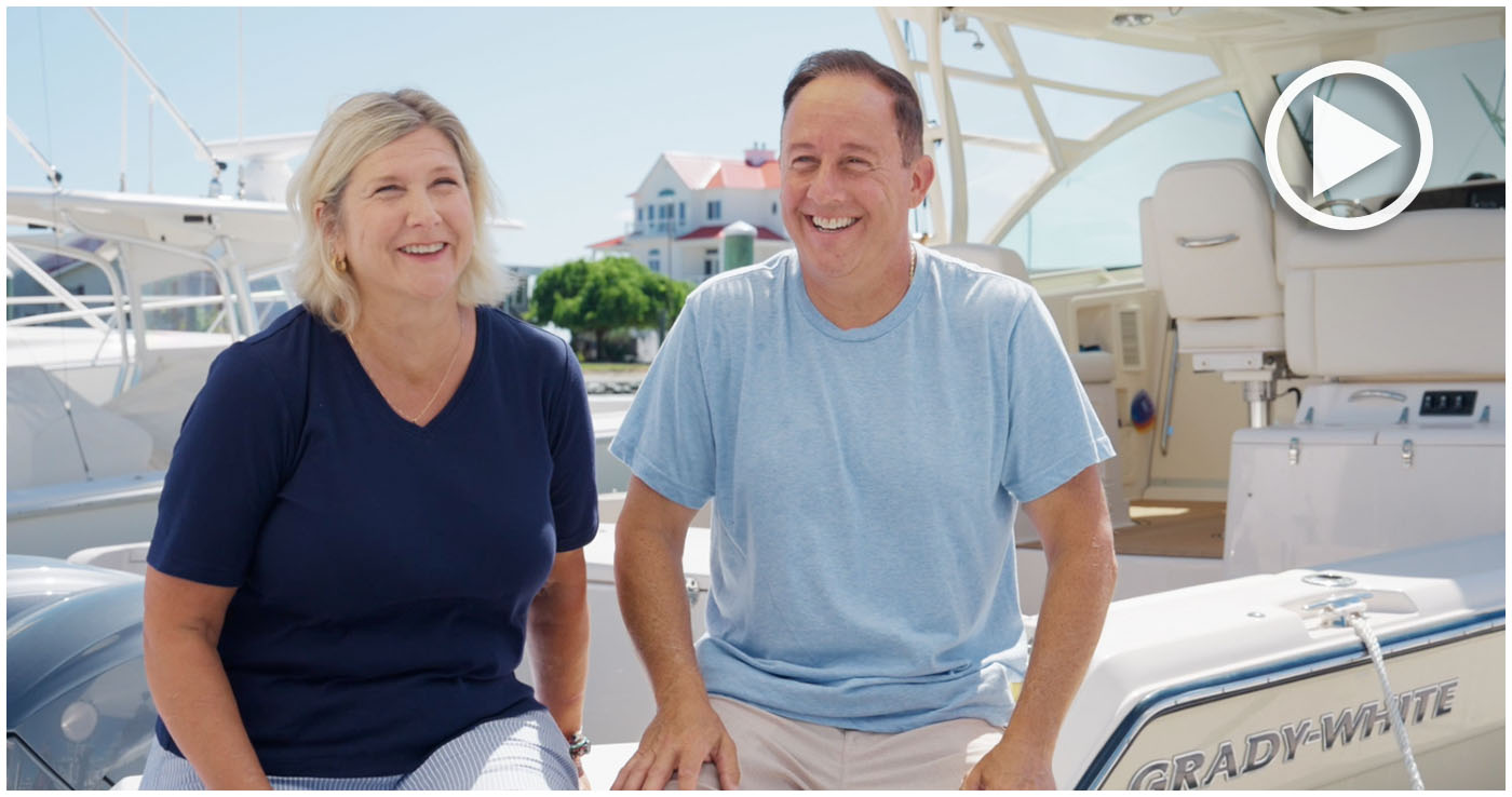 Husband and wife laughing while sitting on their Grady-White boat at a dock.