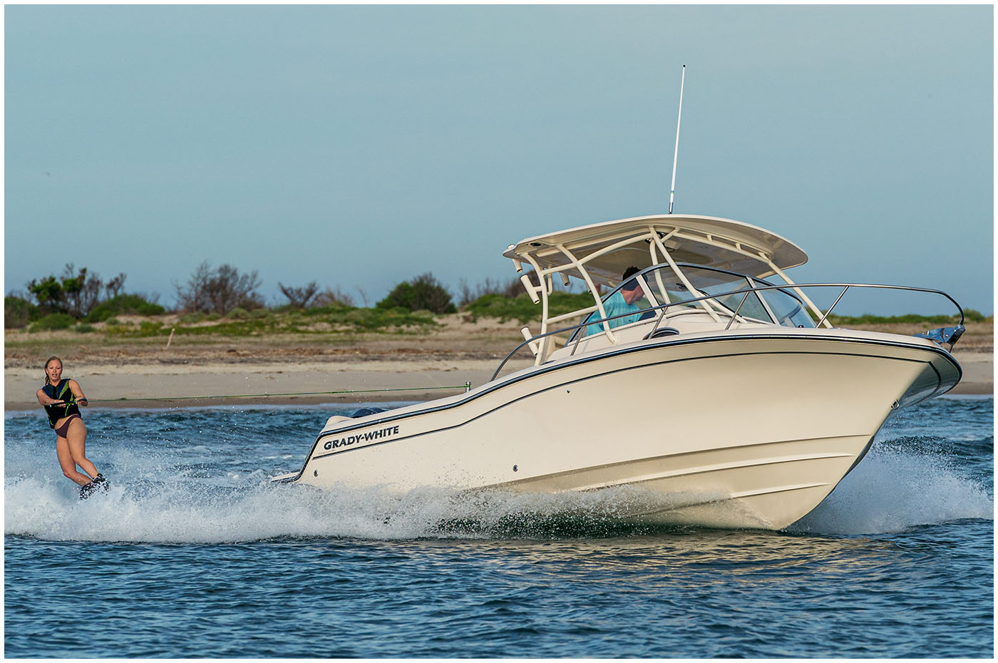 Adventure 218 walkaround cabin boat running starboard side and towing a water skier.