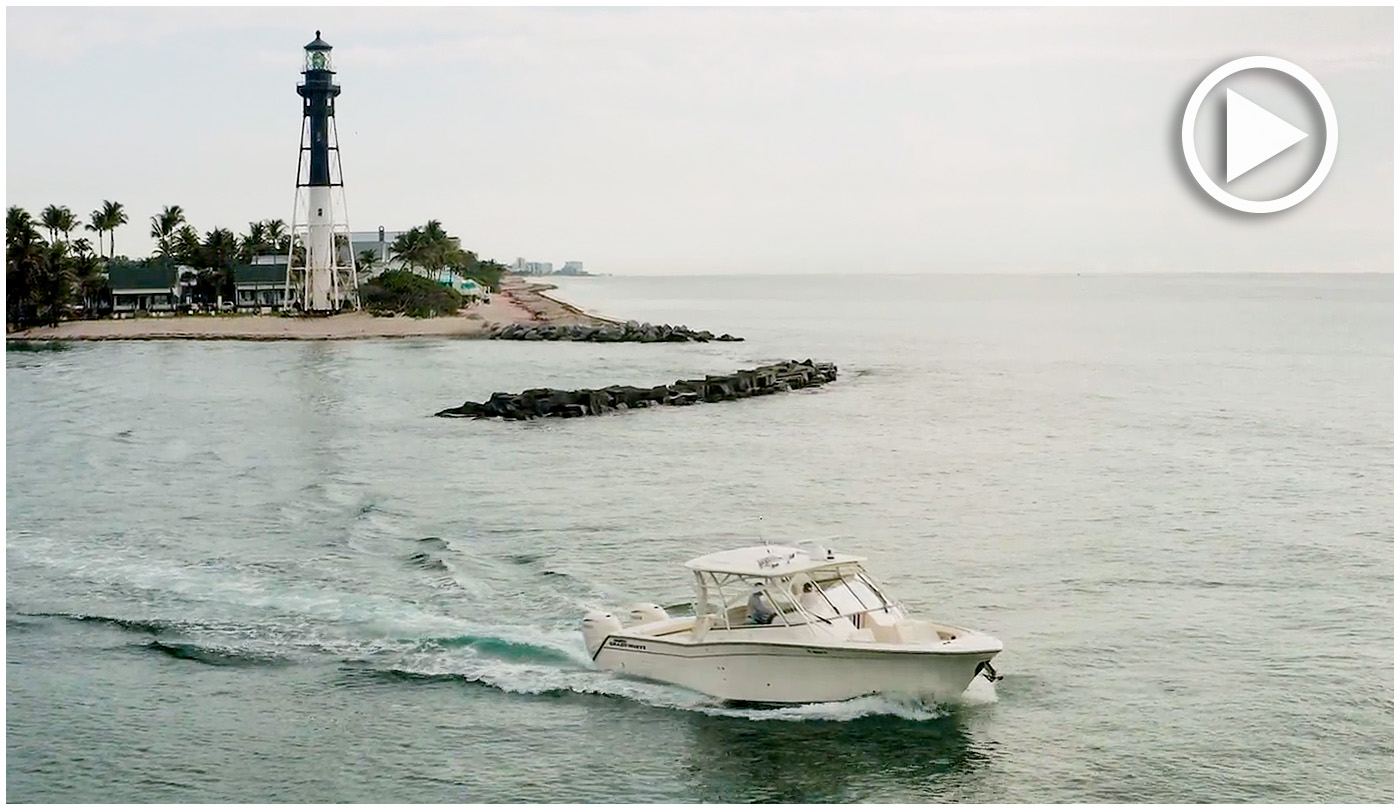 Grady-White Freedom 335 starboard side cruising near a beach with a lighthouse in the background.