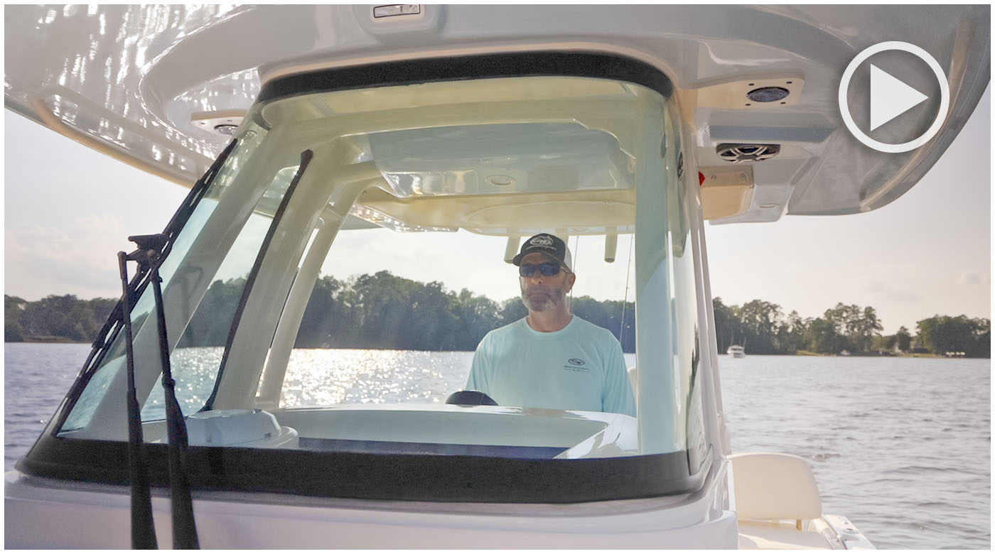 Man standing at the helm and looking through the windshield of a 281 CE Coastal Explorer boat