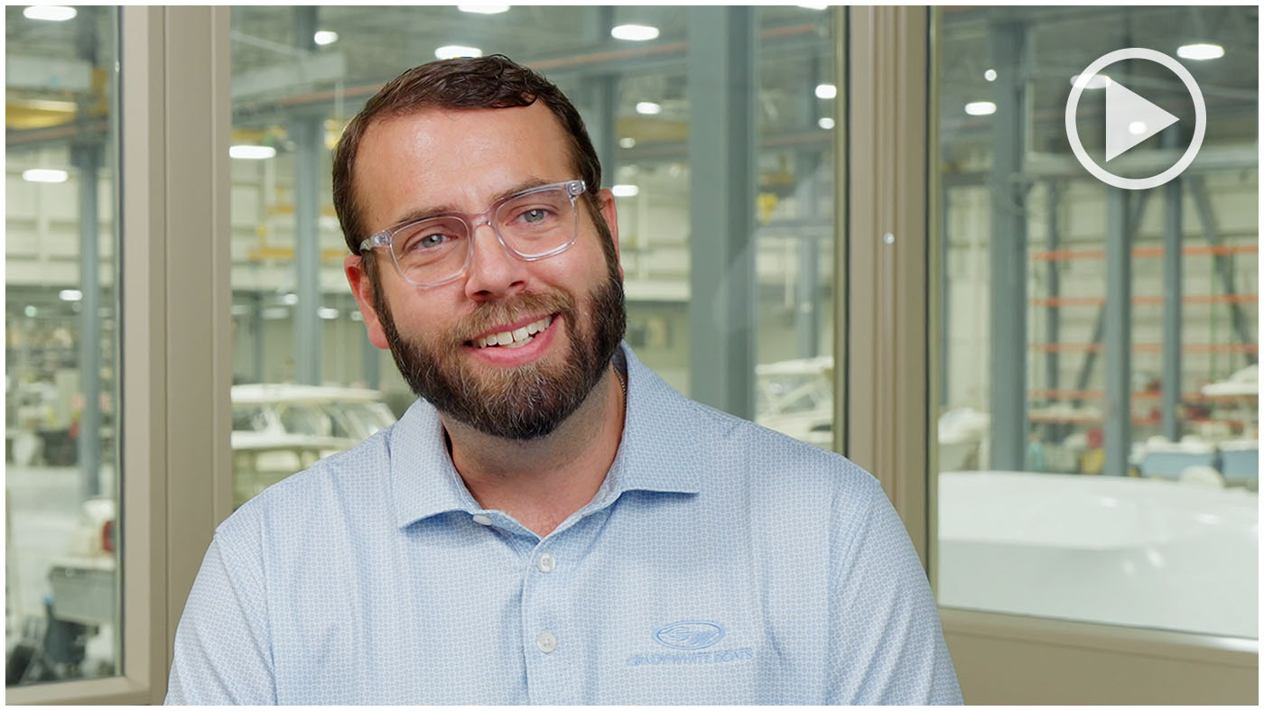Christian Carraway smiling at camera while being interviewed with factory scene in the background