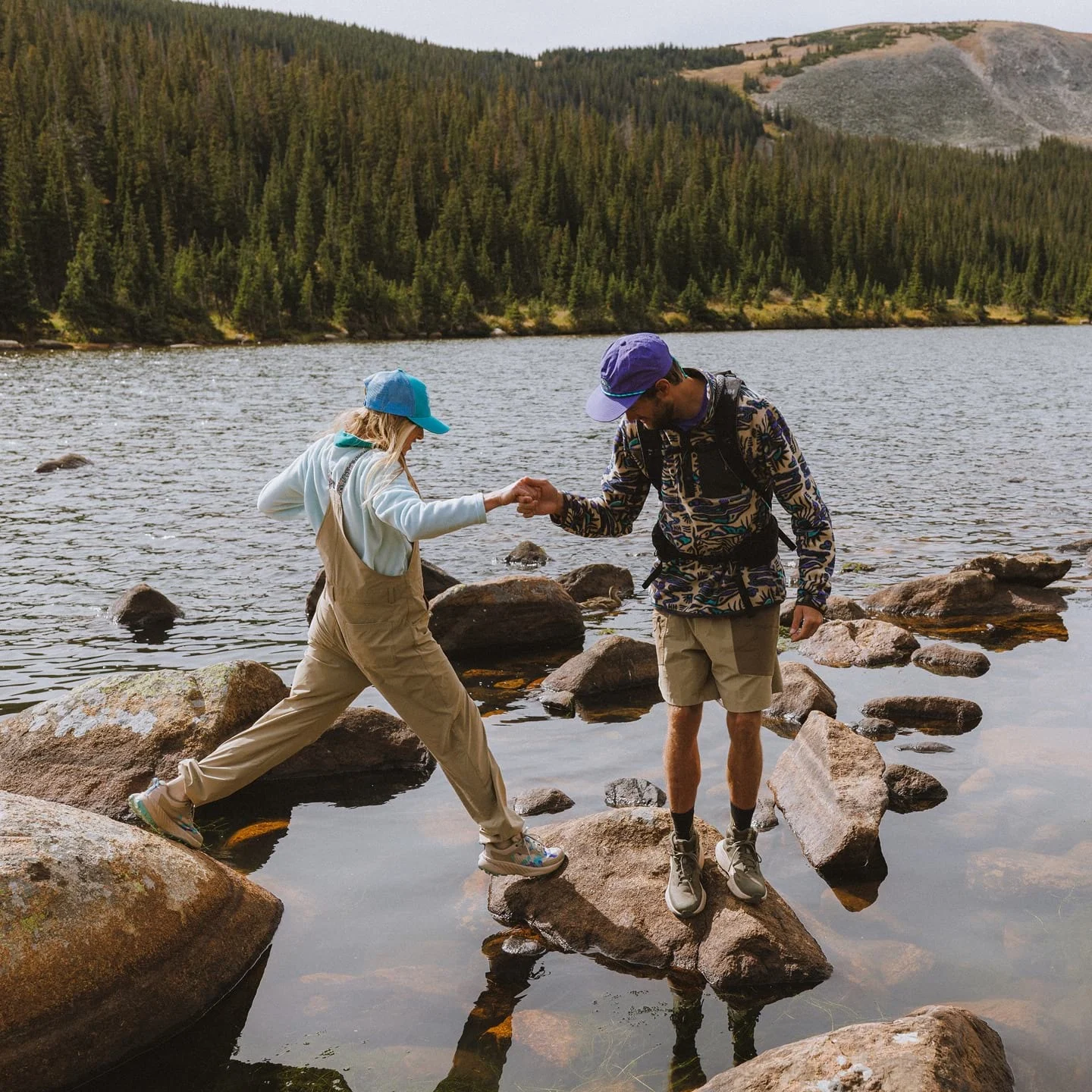 Two hikers in Helly Hansen gear on the shore of a lake