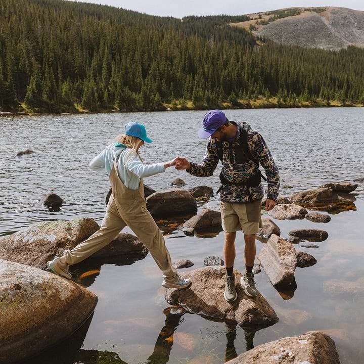 Two hikers in Helly Hansen gear on the shore of a lake