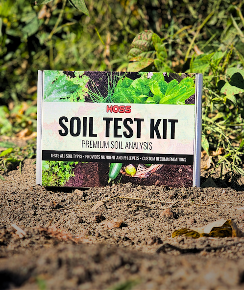 HOSS Soil Test Kit box sitting in garden soil, labeled “Premium Soil Analysis” with images of vegetables on the packaging.
