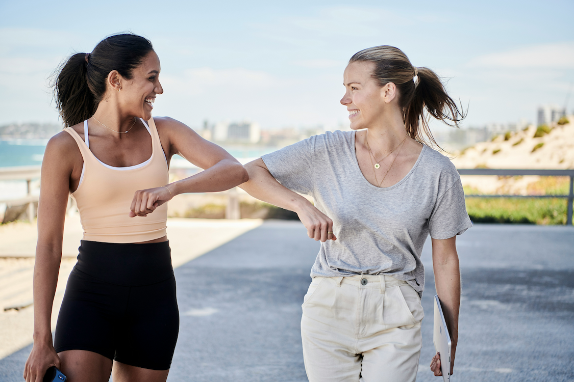 an image of two women walking down a street talking