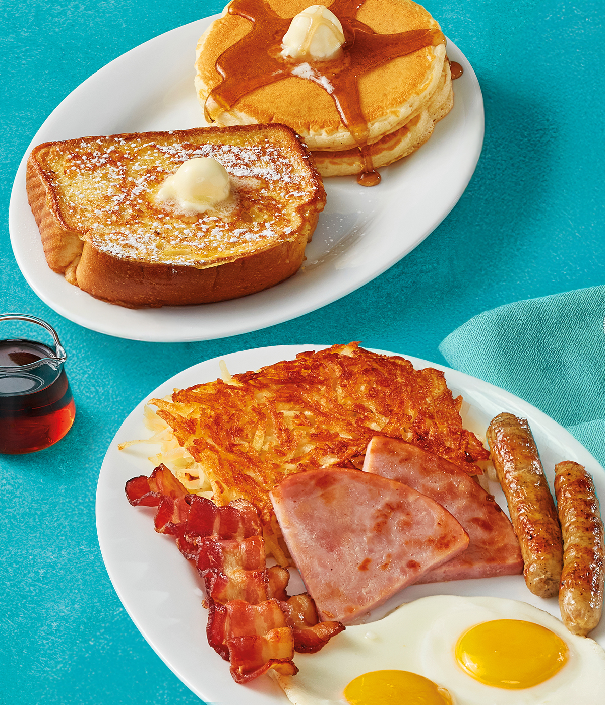 Two eggs served your way, two pork sausage links, two slices of thick-cut ham, two strips of hickory-smoked bacon, and hash browns on a plate. Served with 2 buttermilk pancakes topped with syrup and butter, along with a slice of Classic Thick 'N Fluffy French  Toast.