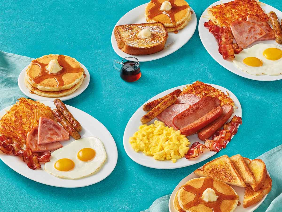 An assortment of IHOPs BreakFEAST meals on table with a blue tablecloth.