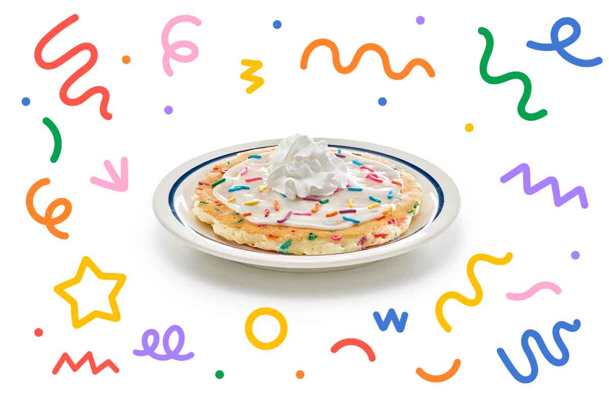 Pancake with sprinkles, icing, and whipped topping.