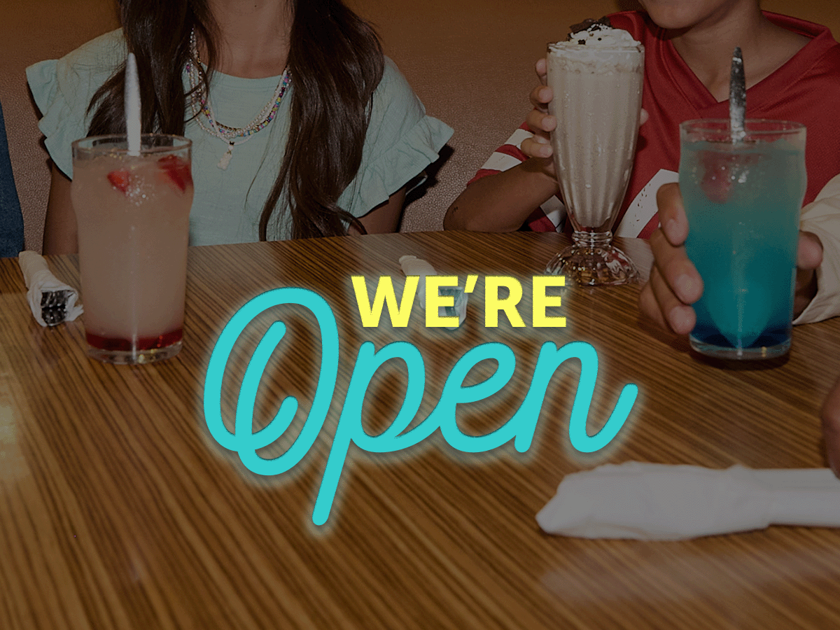 We’re Open text is centered on a soft-focus image of a tightly cropped photo of young people with beverages at an IHOP booth.