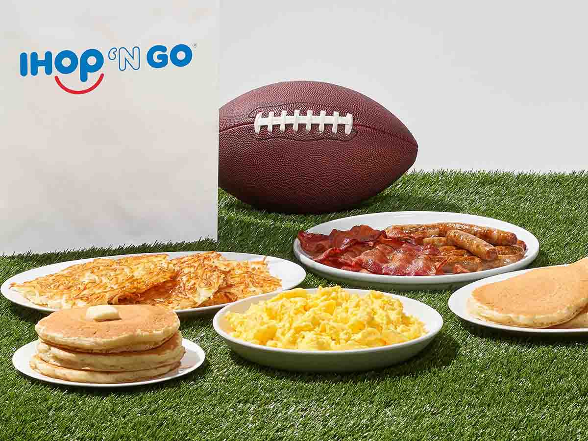Plates of IHOP food sit on turf, with a football and IHOP 'N GO bag behind them.