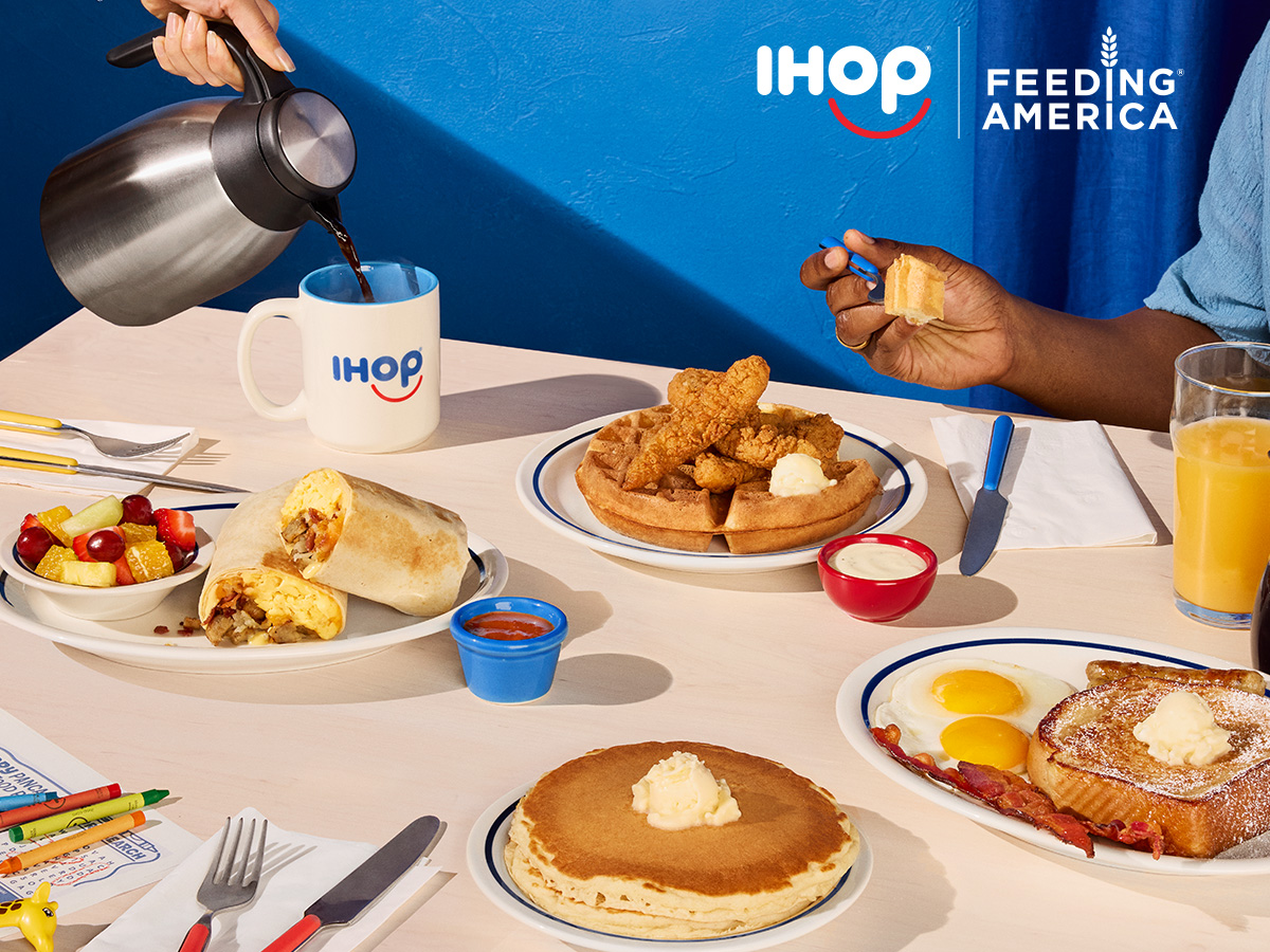 A booth at IHOP featuring several different food items including pancakes, French Toast, chicken and waffles, and a burrito.