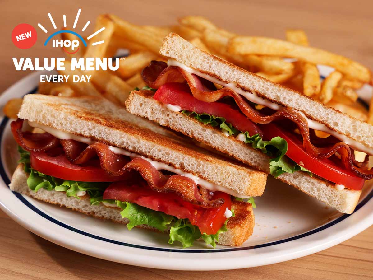 The Value Menu BLT is on a plate with fries on a wood table.