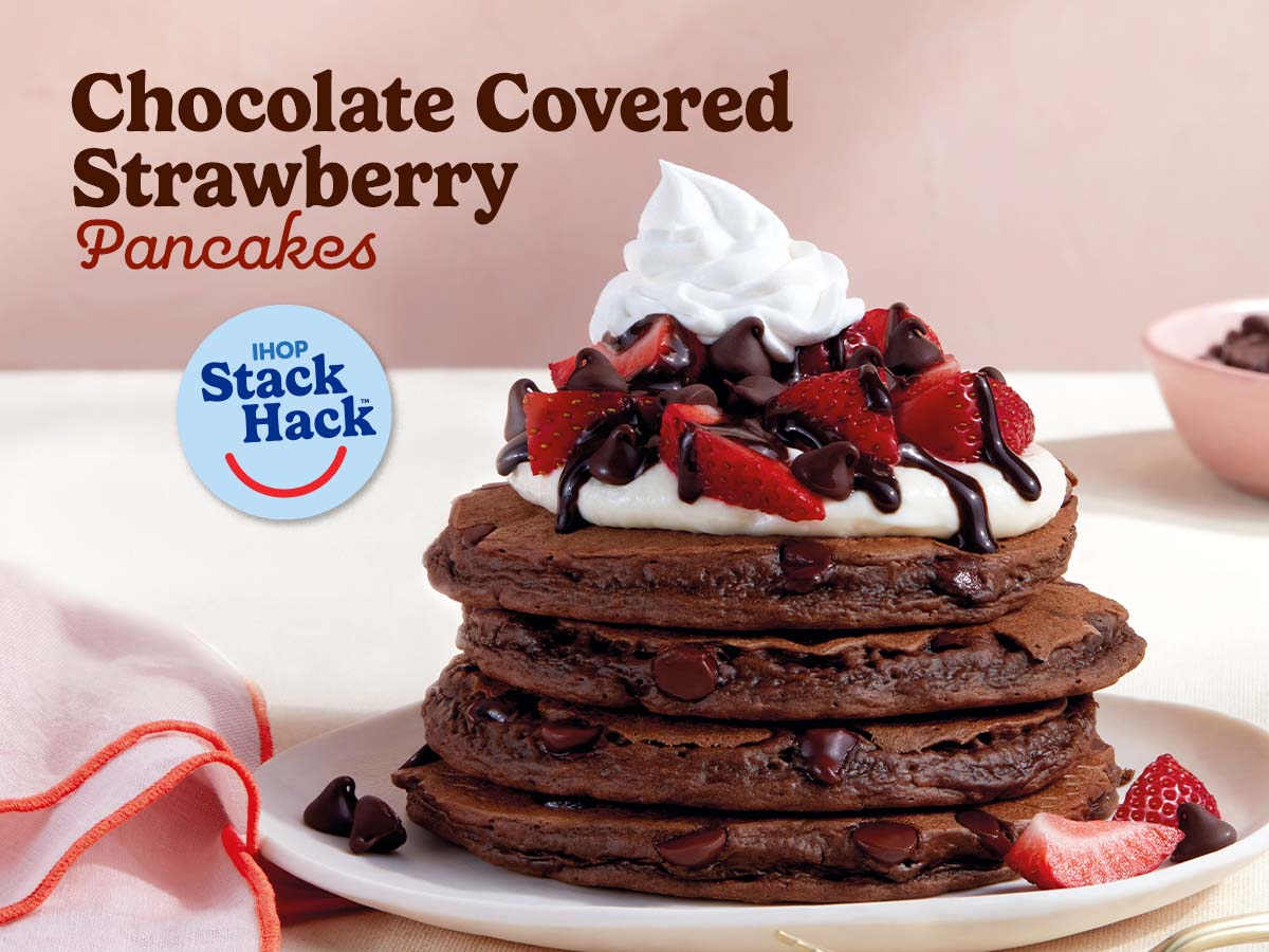 A full stack of Chocolate Covered Strawberry pancakes on a plate, with a pink napkin beside on it, on a white tablecloth