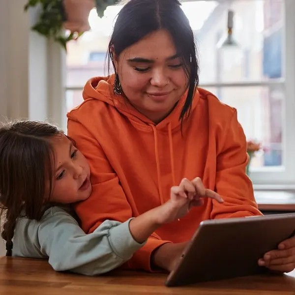 a woman and child looking at a tablet
