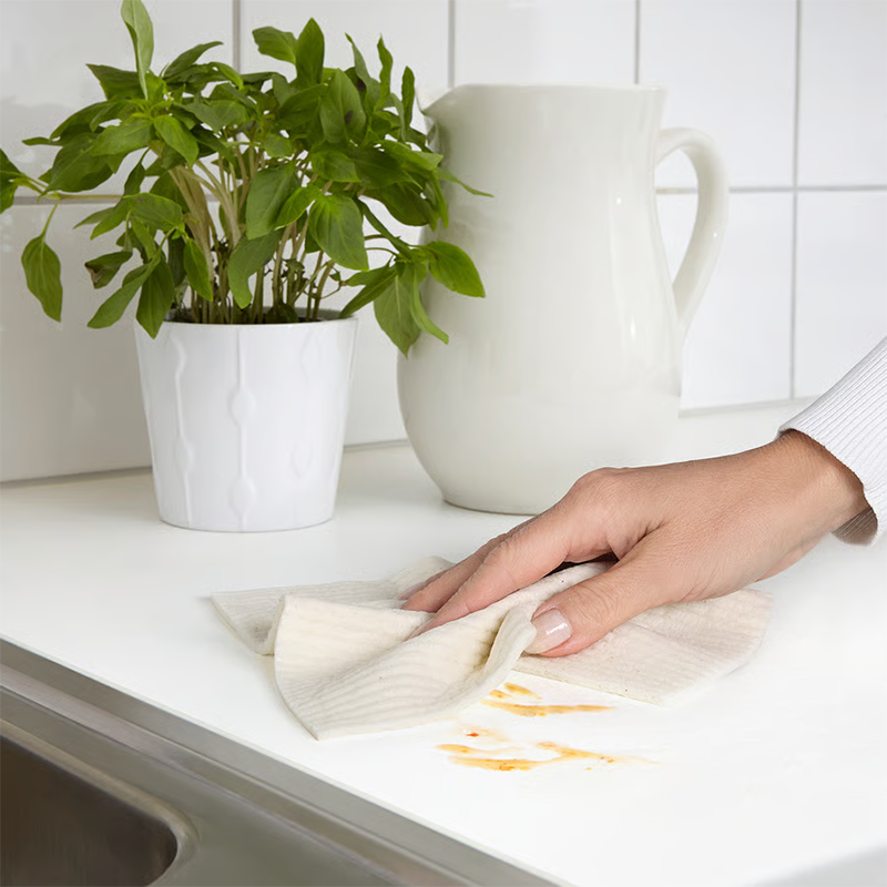 Beige cleaning cloth wiping countertop. 