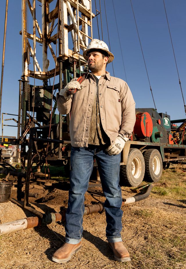 A ma wearing Justin Ames 11" Steel Toe Waterproof boots in walnut brown.