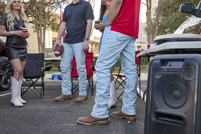 A group of young men wearing Jusin Jeans while tailgating a football game.