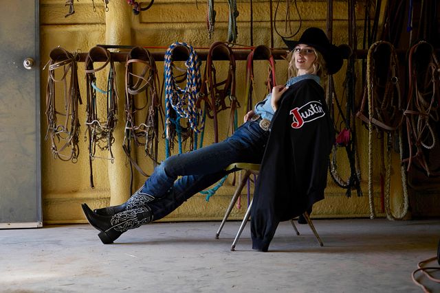 A woman wearing Justin Jeans while sitting in a barn.