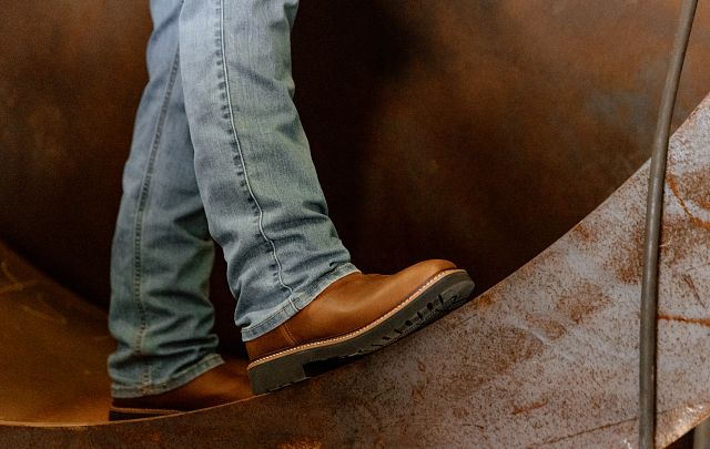 A man wearing the Ames 11" Steel Toe boots in walnut brown.