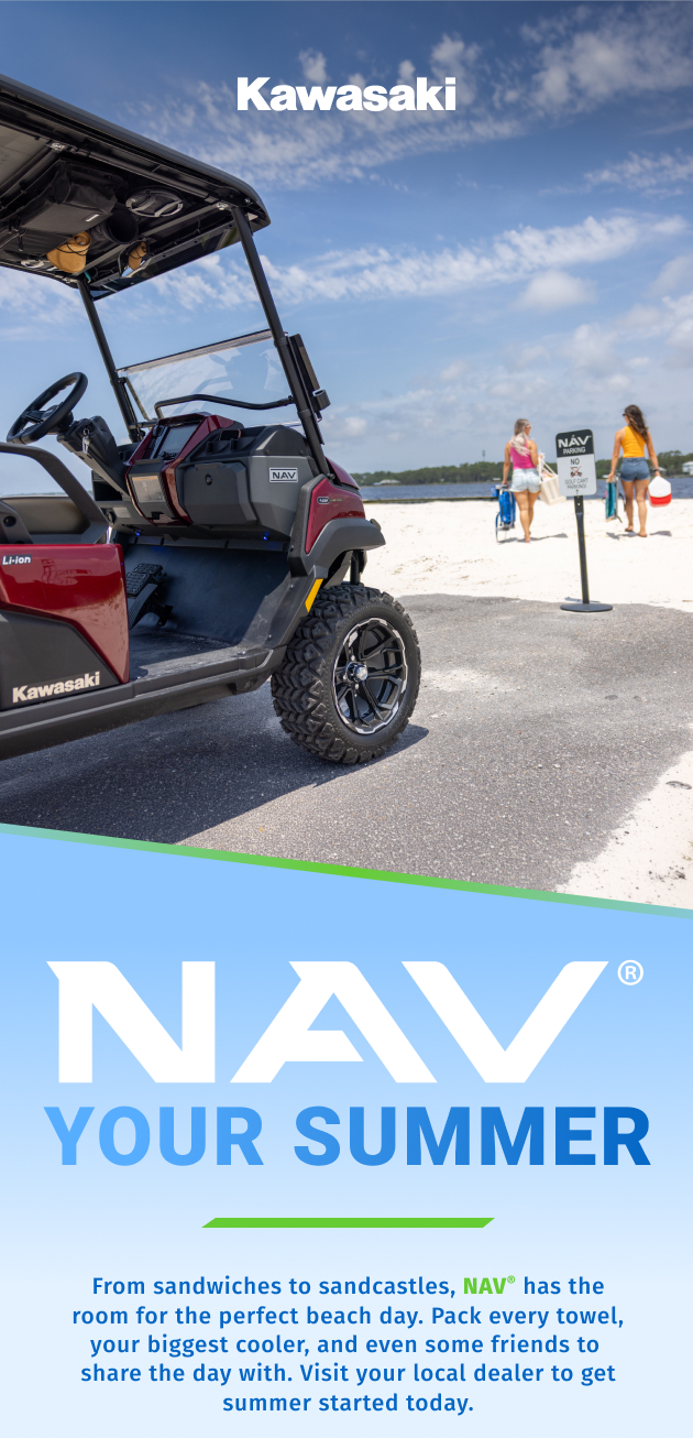 A Kawasaki off-road utility vehicle parked near a beach with two people walking in the background