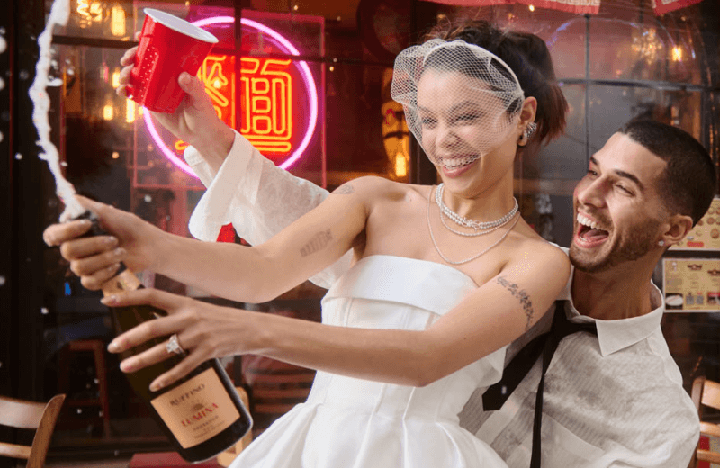 Bride and groom popping champagne. Bride wearing elegant jewelry.