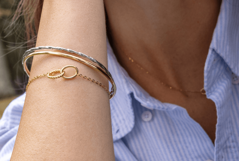 Woman showcasing stacked bracelets and necklace