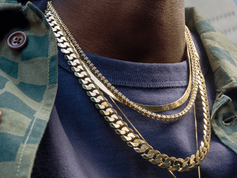 Male showcasing many gold necklaces.
