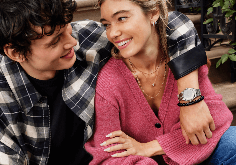 Couple embracing showcasing necklace, earrings, bracelet, watch and ring.