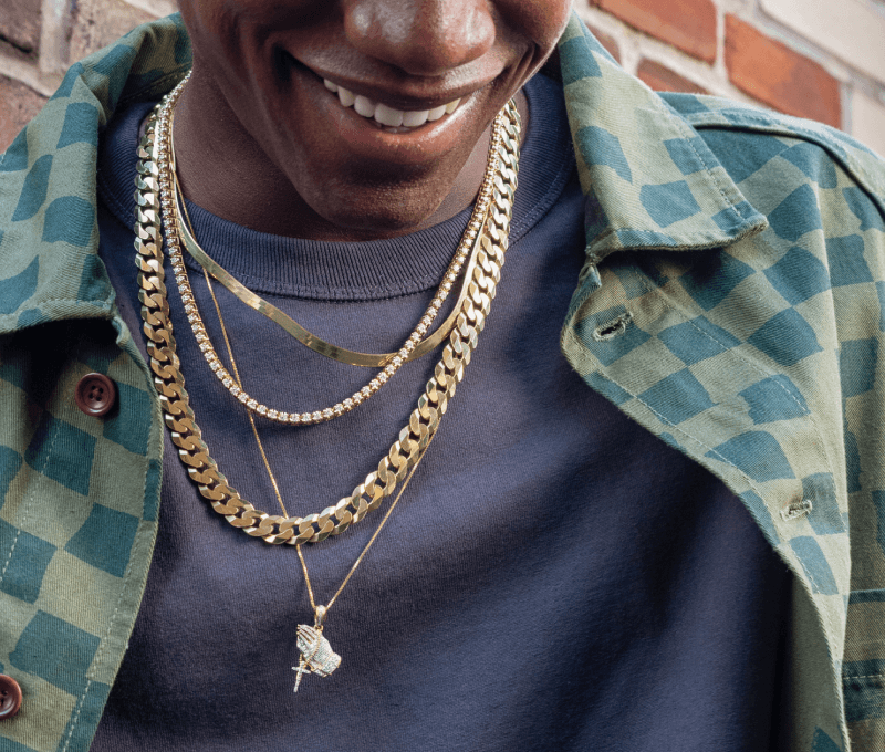 Man showcasing multiple chains and necklaces.