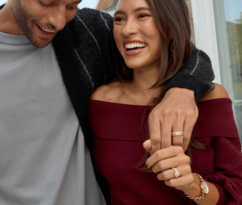 Couple showcasing men and women's rings and watch.