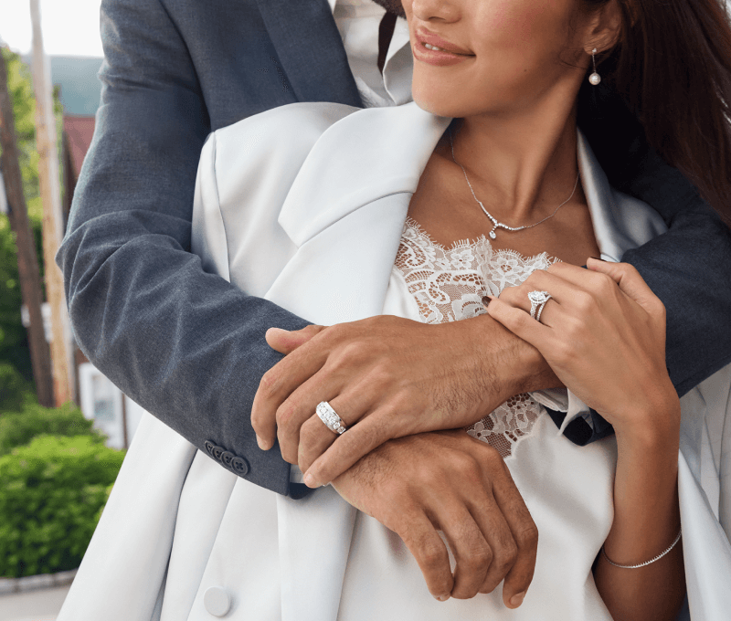 Man embracing woman showcasing earrings, necklace, rings and bracelet.