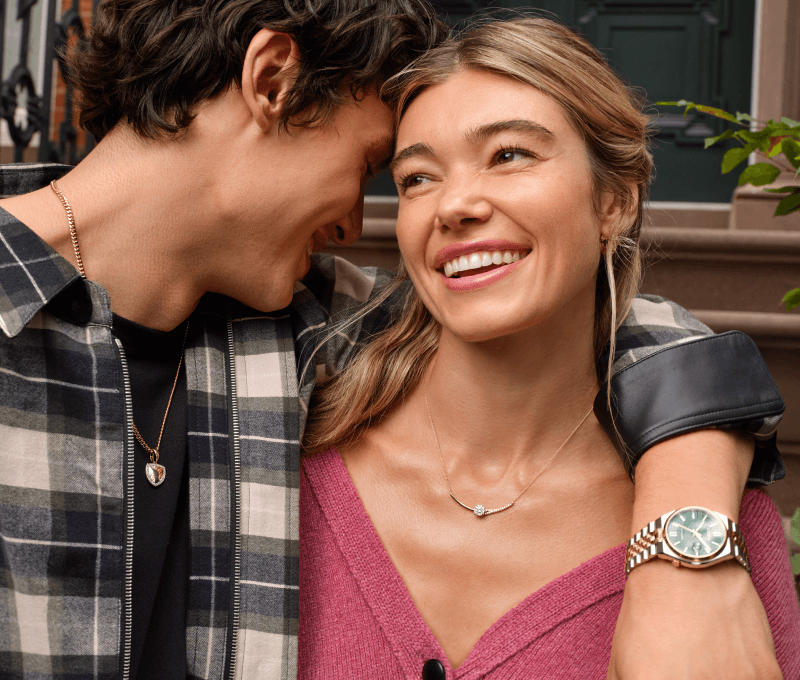 Man embracing woman showcasing watch and necklace.