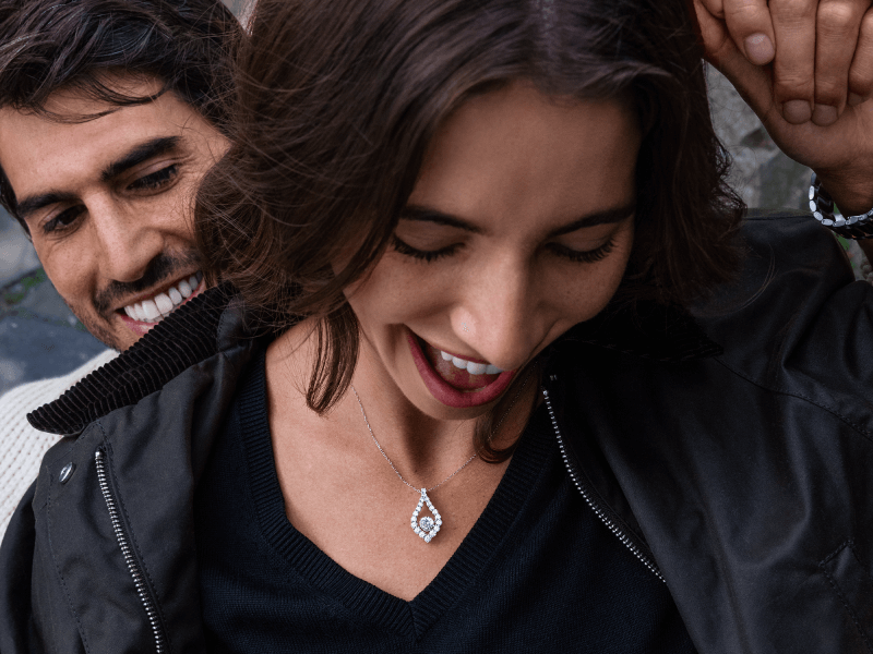 Woman laughing showcasing an Unstoppable Love Collection pendant.