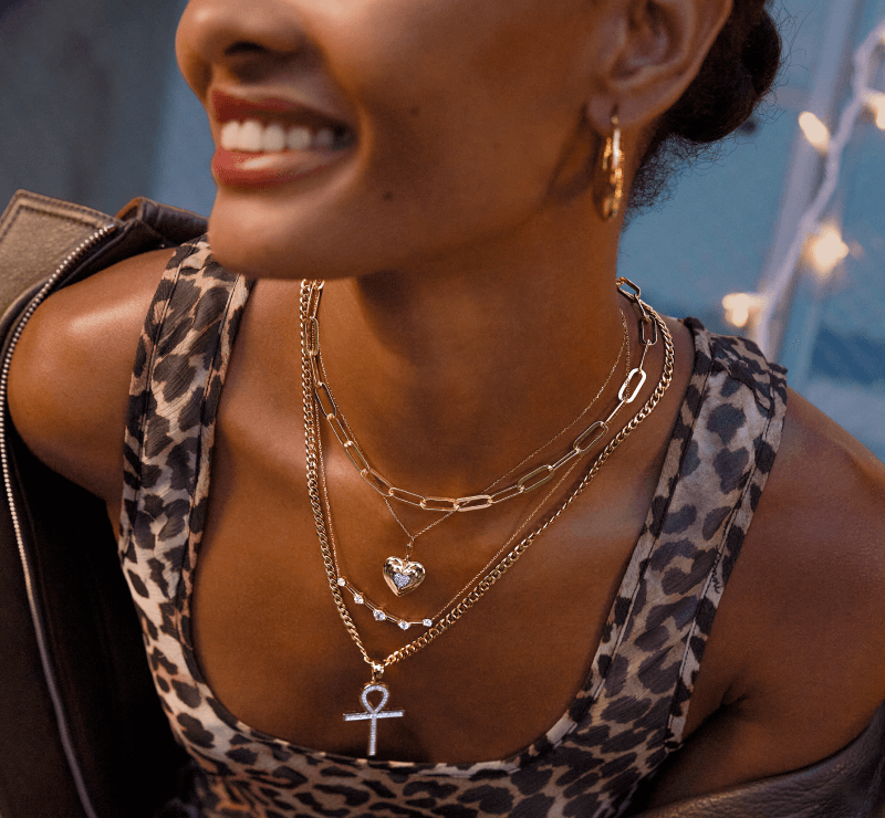 A woman poses, showcasing a variety of beautiful Gold Necklaces