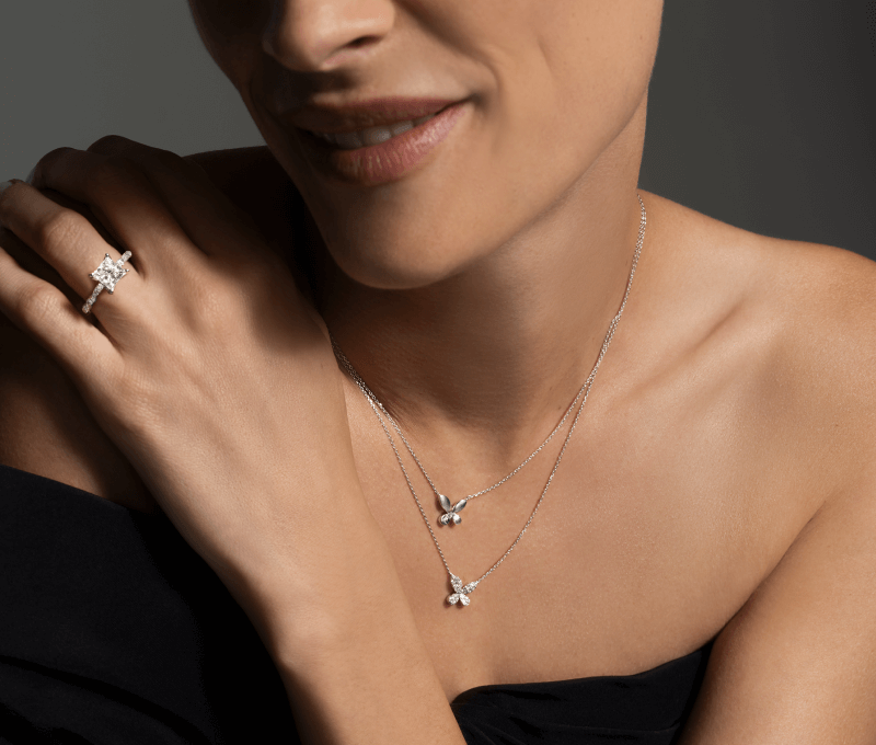 Image showcasing a woman displaying a stunning Diamond Ring paired with two Diamond butterfly Necklaces.