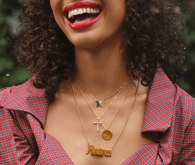 Image of laughing woman showcasing stunning layered gold necklaces