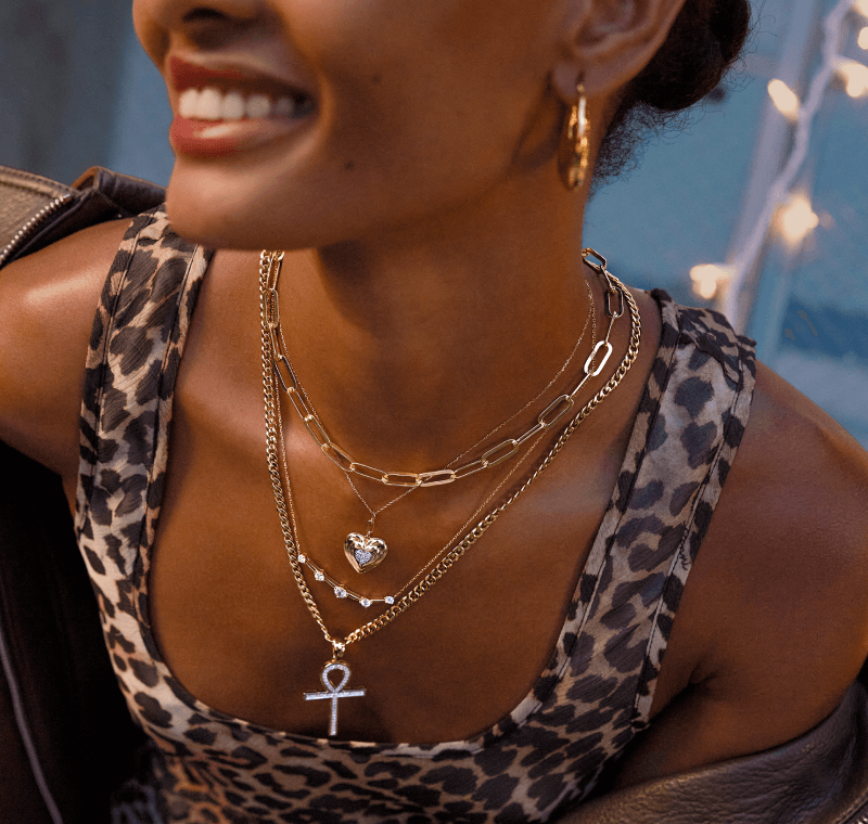 A woman poses, showcasing a variety of beautiful Gold Necklaces and Gold Hoops