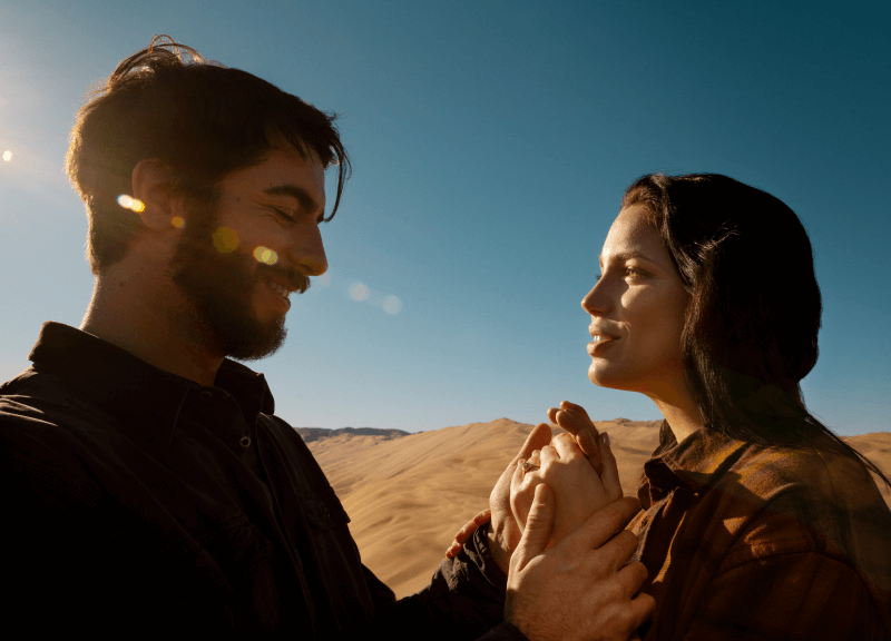 Handsome man holding a beautiful woman's hand in the desert.