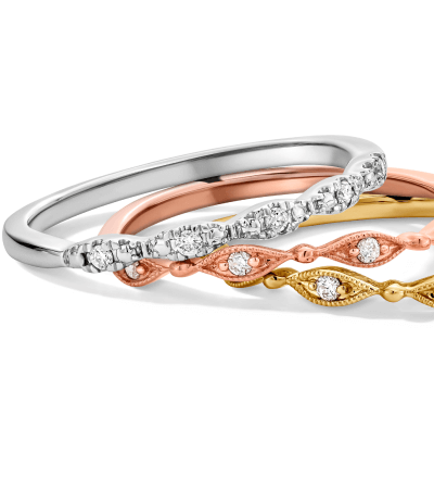 Stackable rings in white, rose, and yellow gold with diamond accents and vintage designs. 