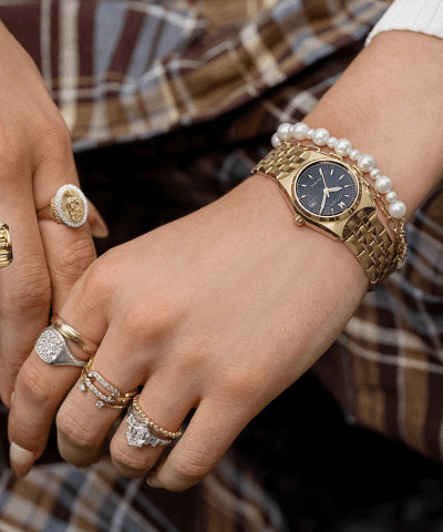 A man poses, showcasing a Gold Citizen Watch and Gold and Diamond Rings