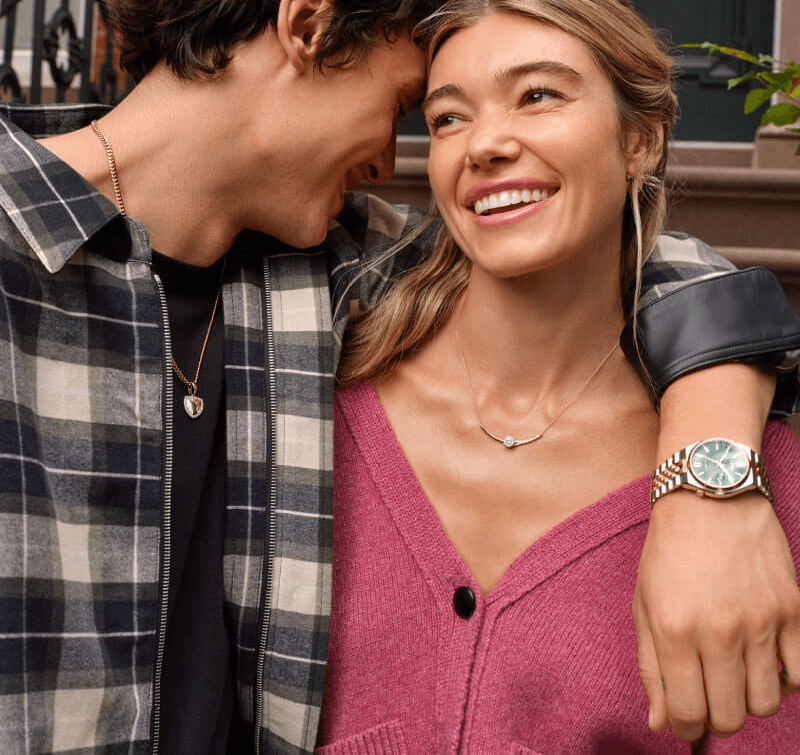 Couple wearing gold necklaces and gold watch, beneath a Valentine’s Day gift guide banner. 