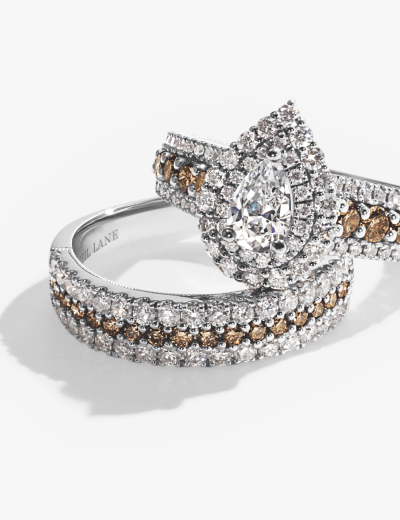 Pear-shaped diamond engagement ring with halo and pavé band, accented with champagne diamonds.