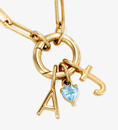 Yellow gold charm necklace with letter A, heart gemstone charm, and toggle clasp.