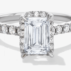 White gold engagement ring with an emerald-cut diamond center and pavé diamond-accented band.