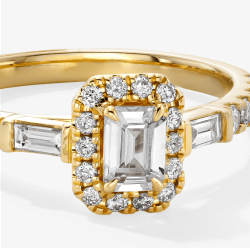 Yellow gold engagement ring with an emerald-cut diamond center, pavé halo, and baguette diamond side stones.