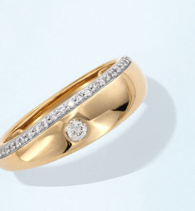 Yellow gold dome band ring featuring a row of small diamonds and a single diamond accent.
