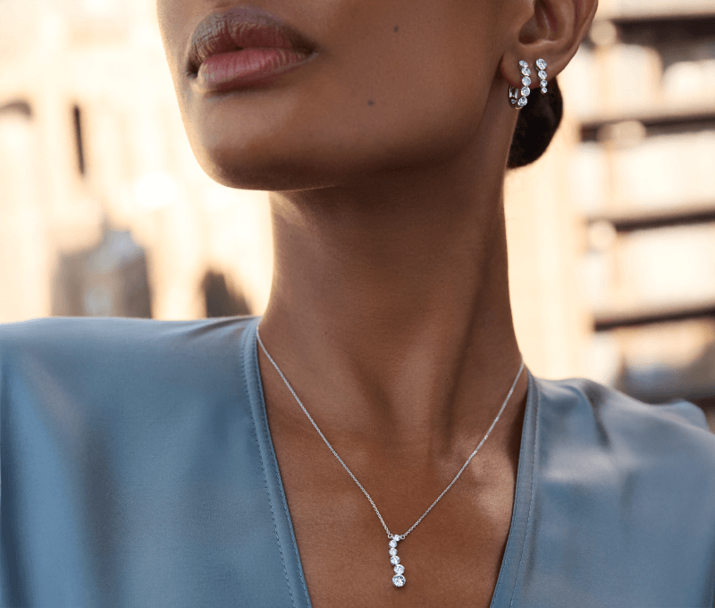 Model Wearing a White Gold Diamond Drop Pendant Necklace and Diamond Hoop Earrings.