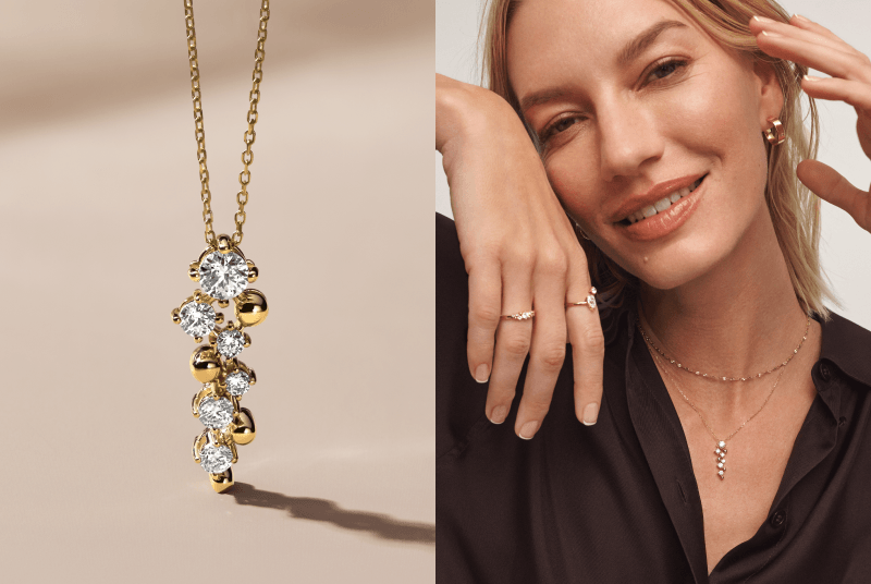 Gold Jouje necklace with unique gold and diamond drop pendant. Woman smiling at camera wearing variety of fine jewelry. 