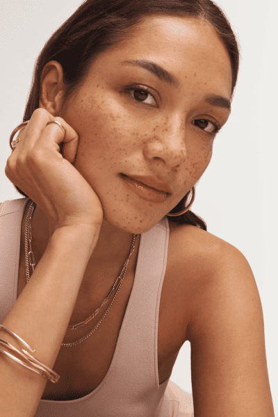 Woman wearing variety of yellow gold fine jewelry.