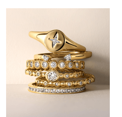 Stacked yellow gold rings with diamond eternity bands and signet ring.